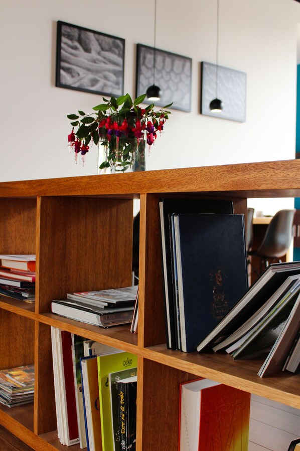 A wooden bookshelf with books and a vase of flowers. - Casa Q (Quito)