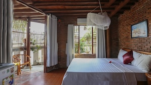Un dormitorio con cama, ventana con cortinas, techo de madera y pared de ladrillo.