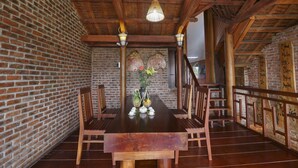 Una mesa de madera con sillas, una lámpara colgante y una pared de ladrillo.