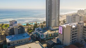 A high-rise hotel overlooking a beach with a pool and palm trees.