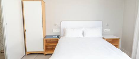A bedroom with a bed, wooden nightstands, a wardrobe, and an air conditioning unit.
