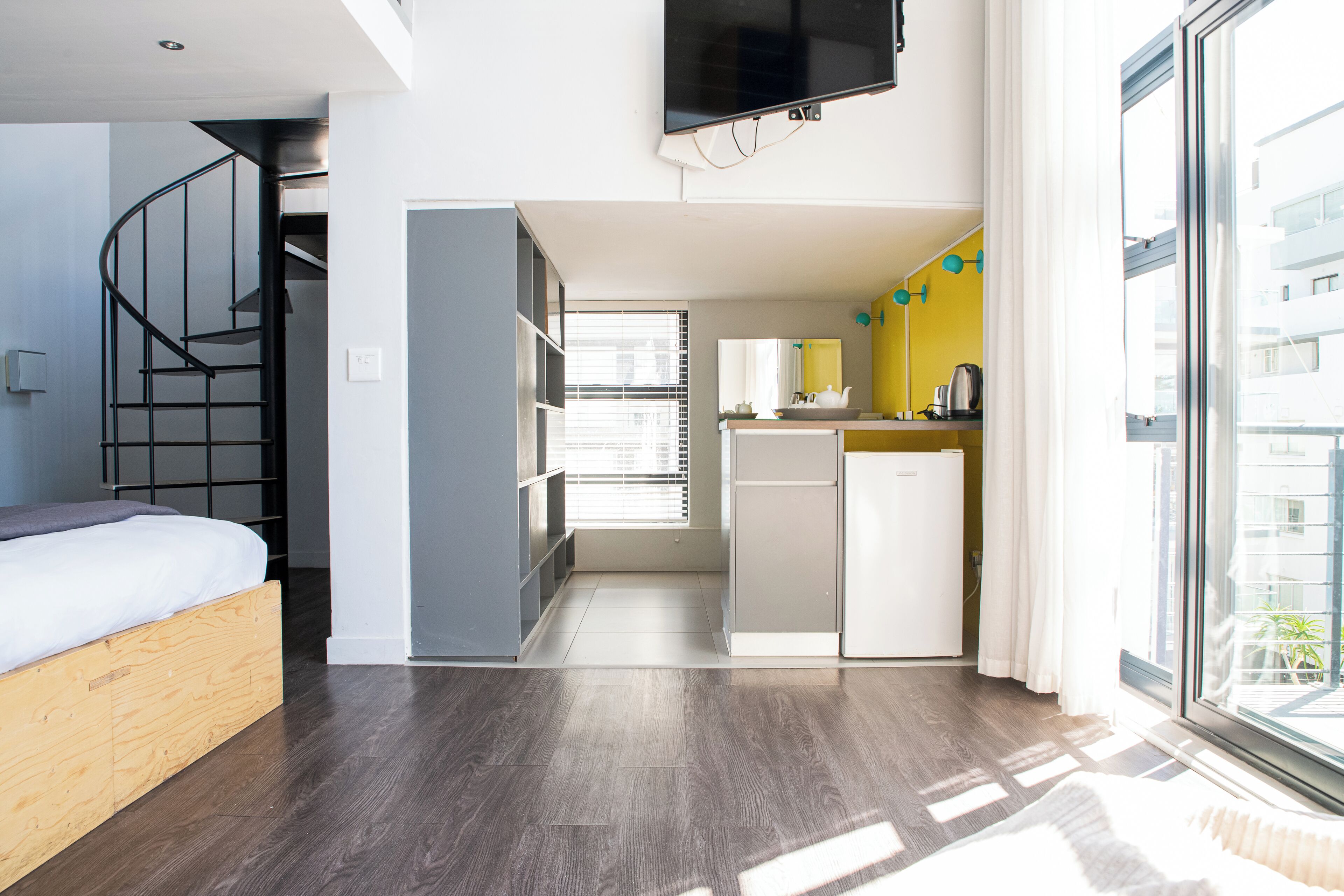 A compact living space with a bed, a kitchen area, and a dining table.