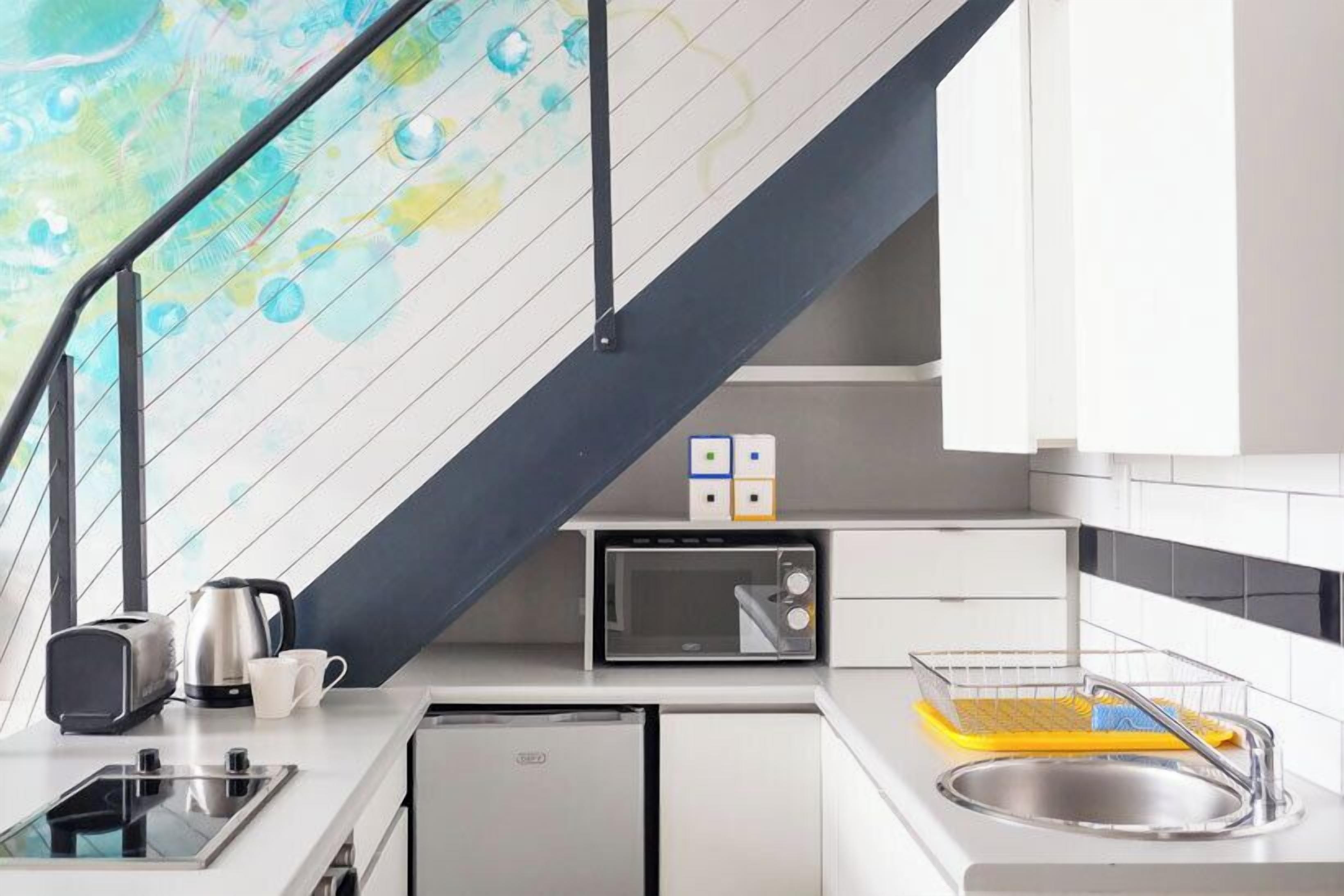 A modern kitchen with a built-in microwave, toaster, and kettle on a white countertop.
