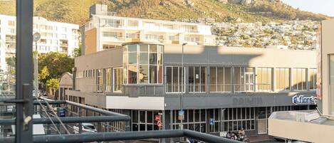 A balcony with a white chair, a view of a cityscape, and a mountain in the background.
