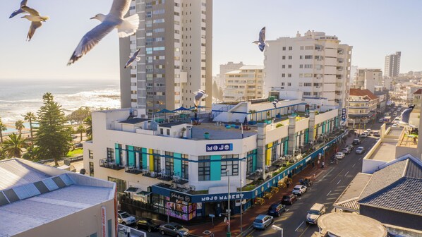 A multi-story hotel with a rooftop terrace, a visible restaurant, and a view of the ocean.