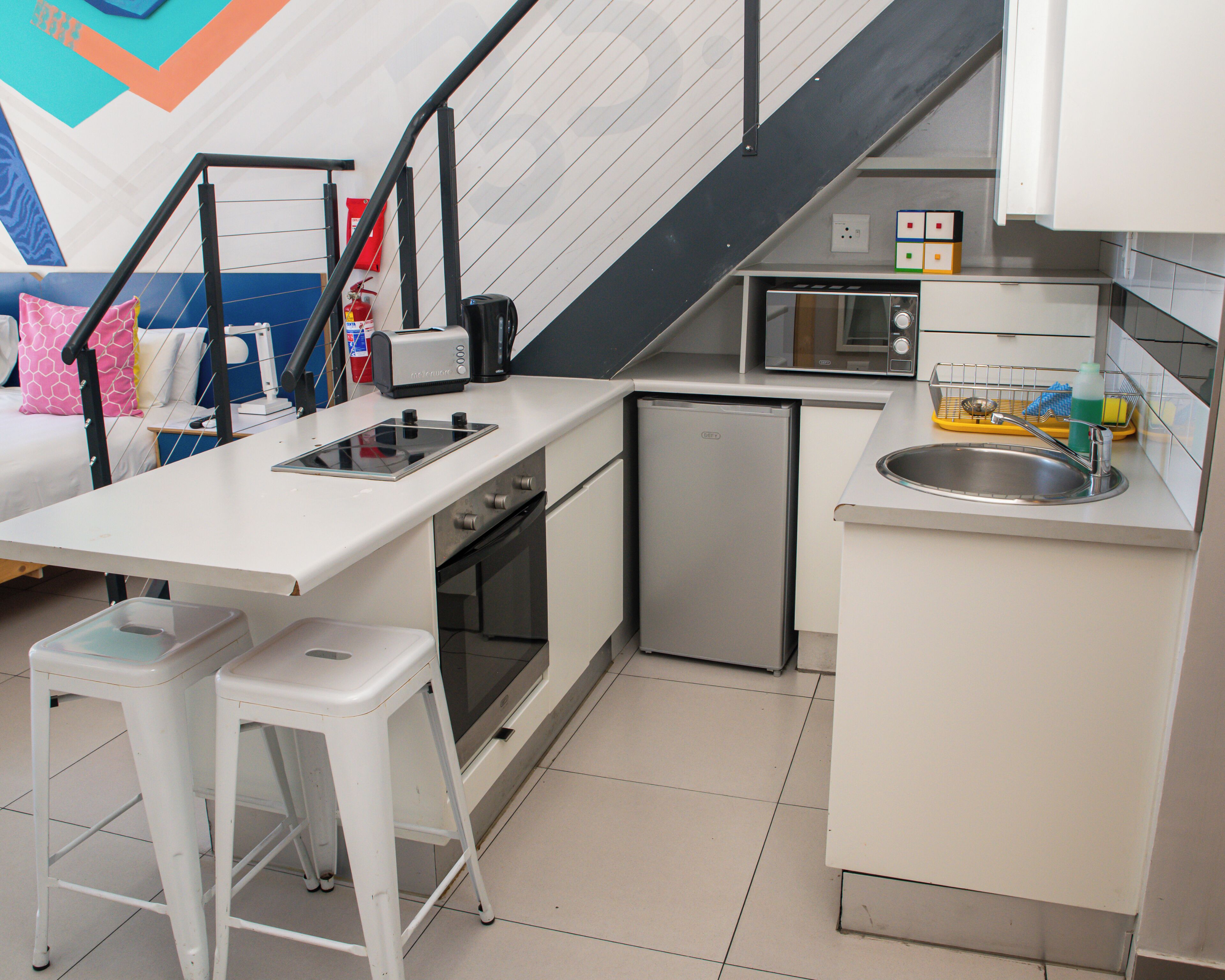 A compact kitchen with a microwave, toaster, sink, and a small refrigerator.
