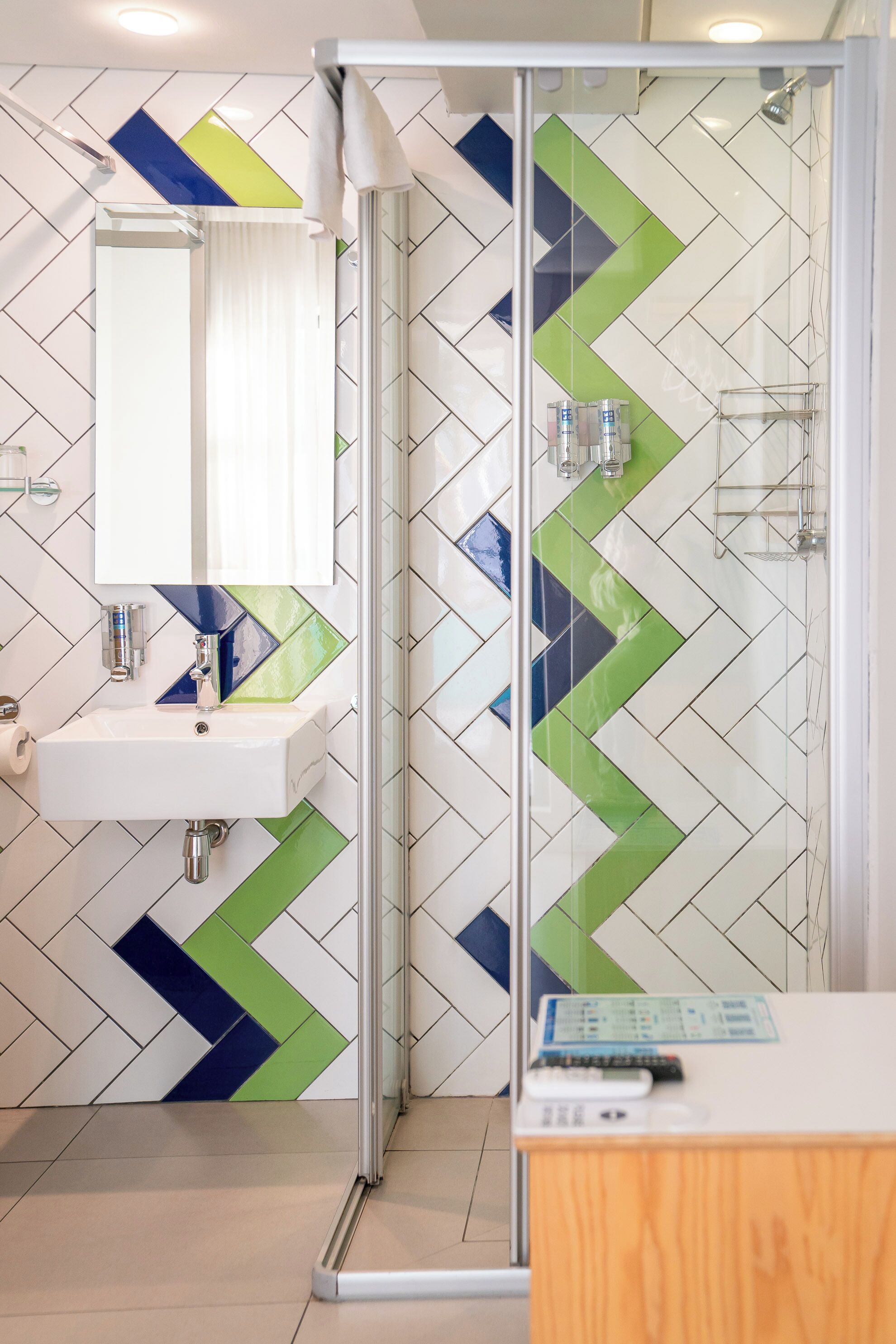 A modern bathroom with a glass shower enclosure, a white sink, and a mirror above it.