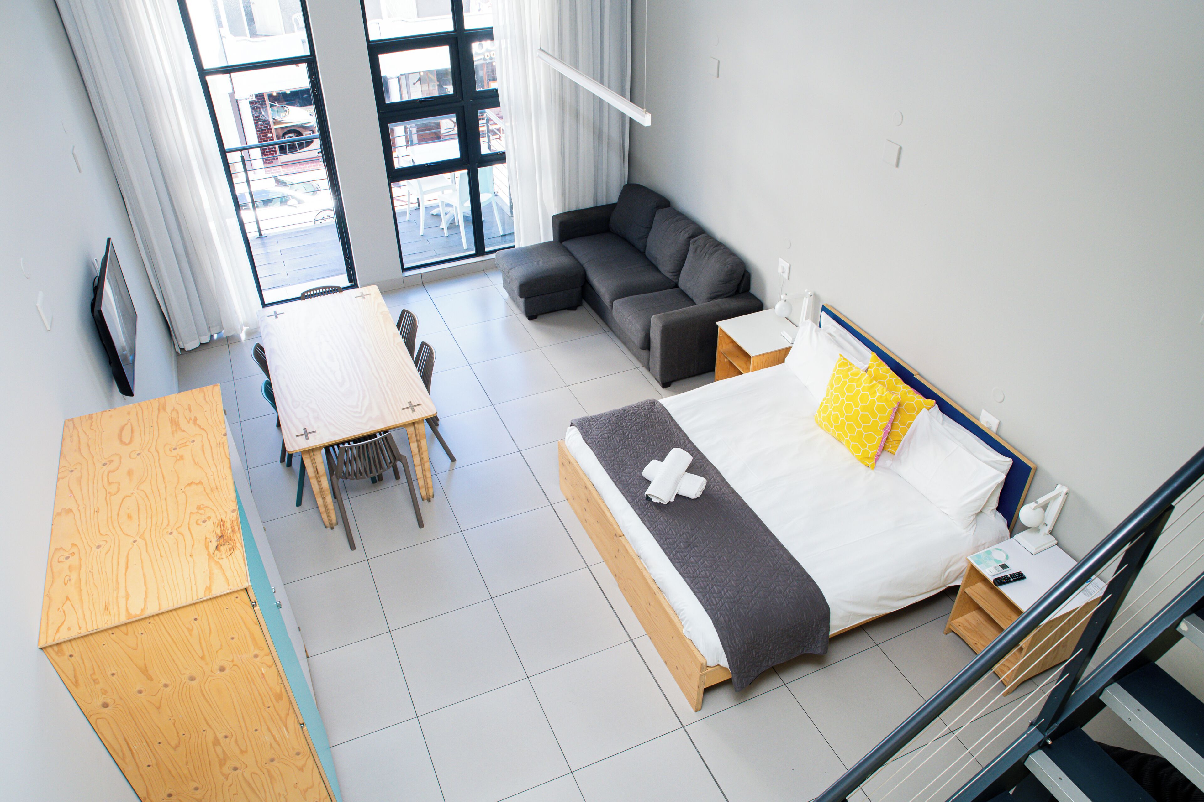 A modern room with a bed, a sofa, a table, and a staircase.