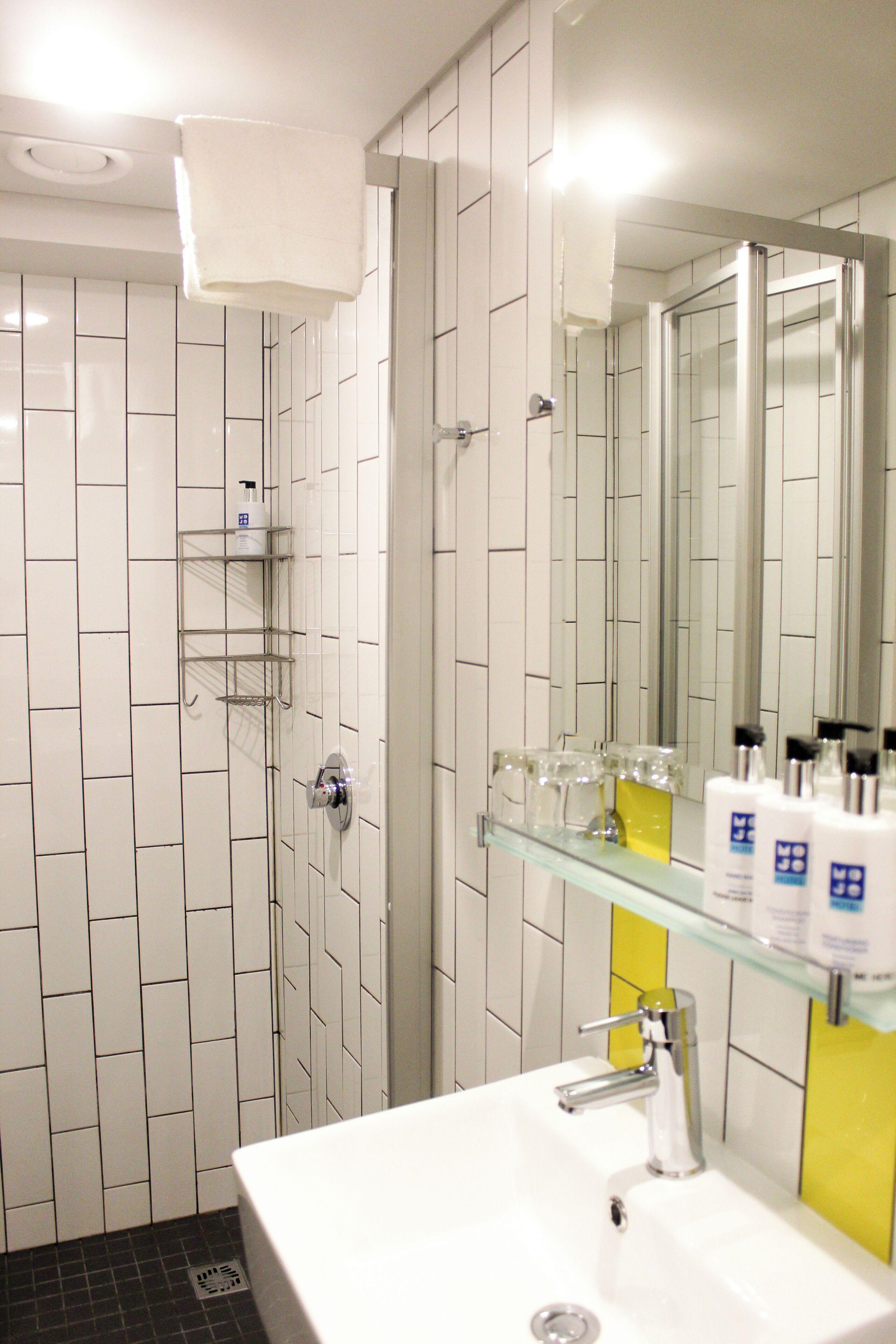 Un baño con un lavamanos blanco, cabina de ducha de vidrio y un espejo.