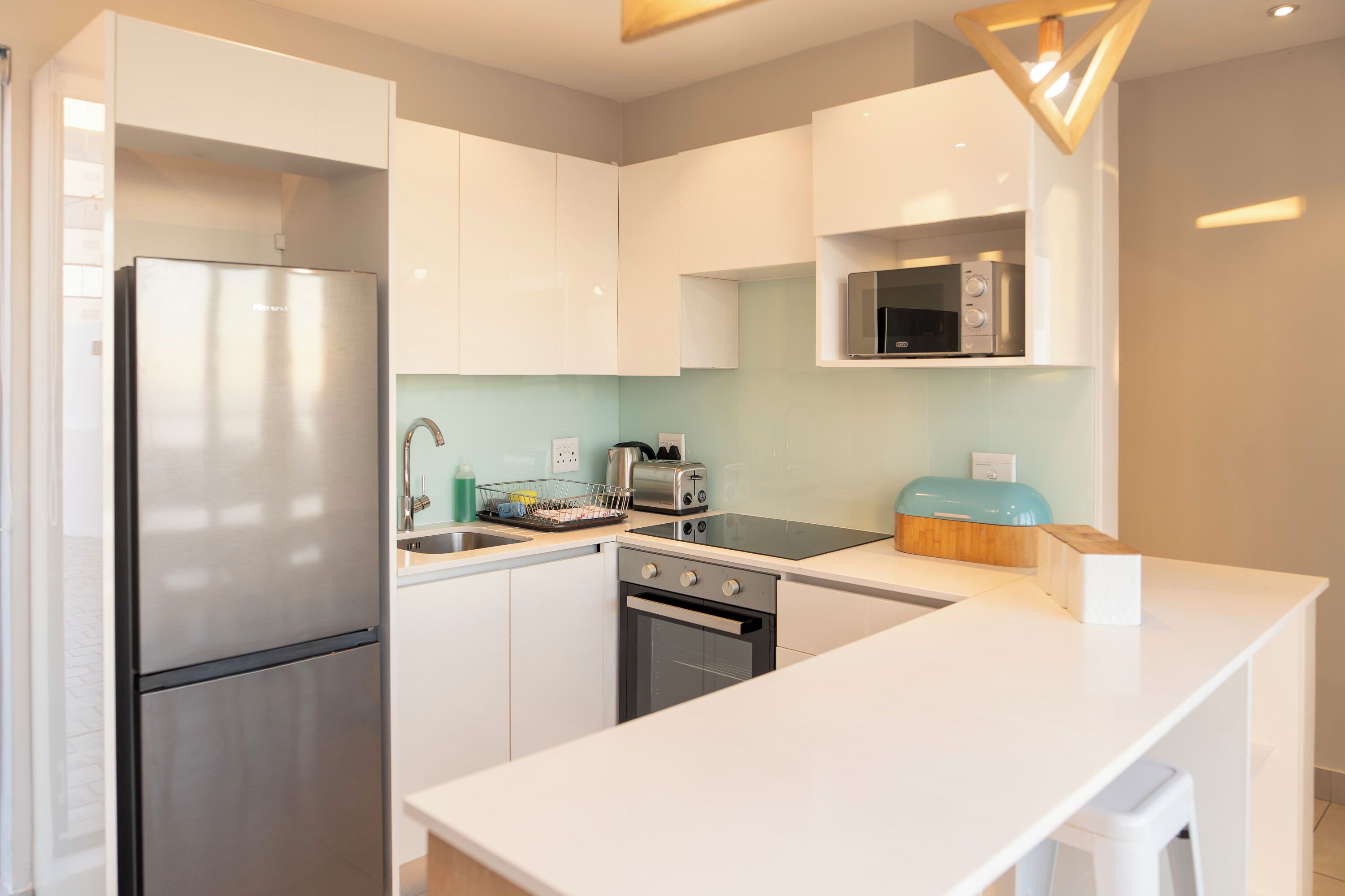 A modern kitchen with white cabinets, stainless steel appliances, and a light blue backsplash.
