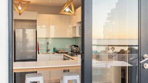 A modern kitchen with stainless steel appliances, a white countertop, and two stools. - Mojo Hotel (Cape Town)