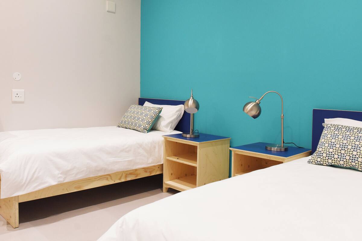 A bedroom with two single beds, wooden nightstands, and a built-in wardrobe.