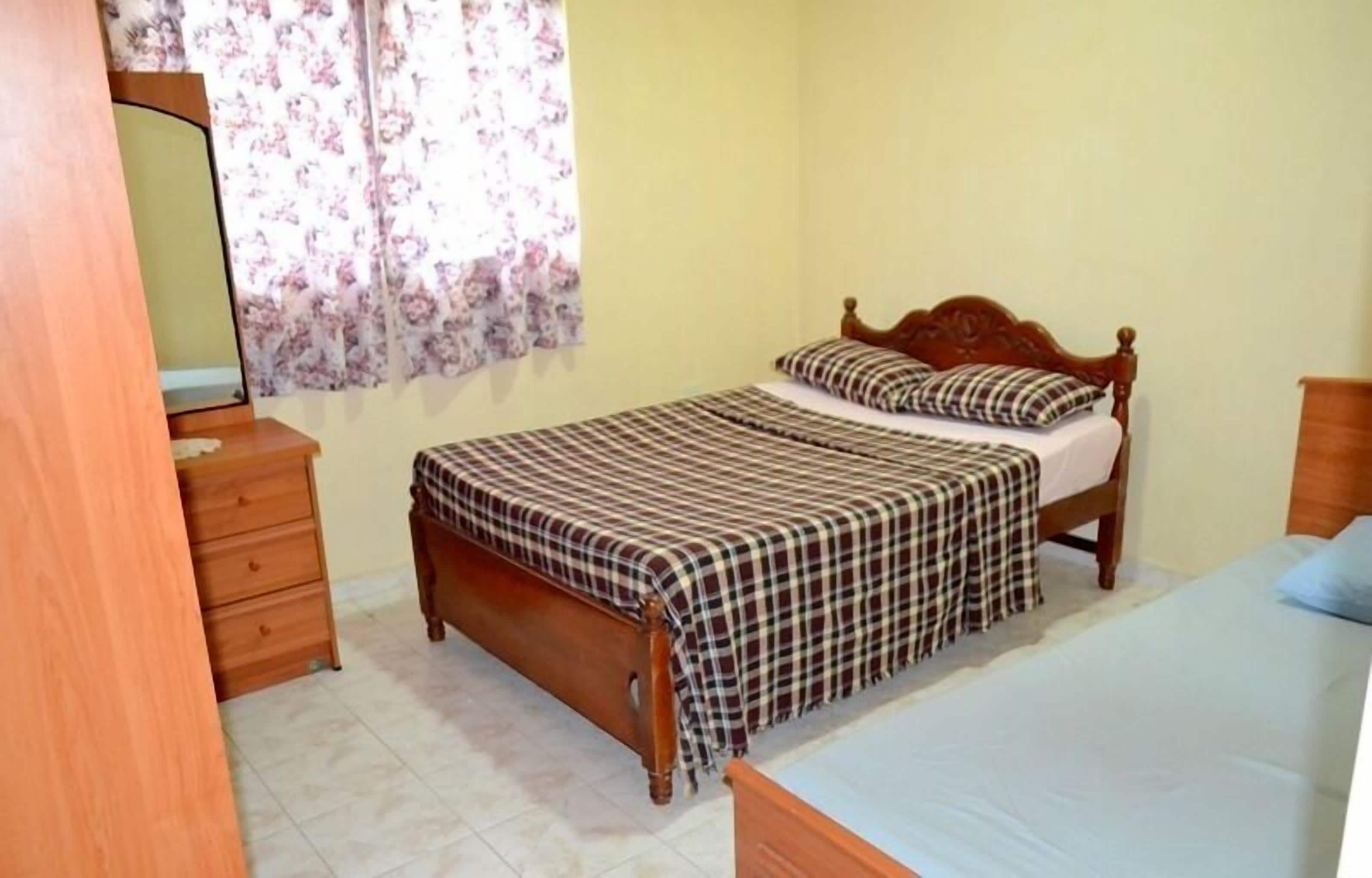 A bedroom with a bed, a wooden dresser, and a mirror.