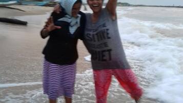 Two individuals standing in shallow water at a beach with waves.
