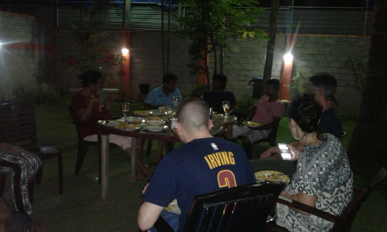 A group of people dining outdoors at a table with chairs and plates of food.