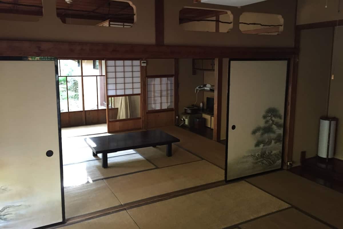 Een traditionele Japanse kamer met tatami vloerbedekking, schuifdeuren en een lage tafel.