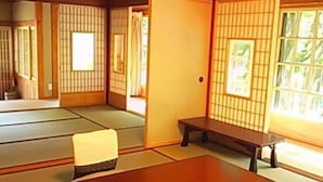Una habitación japonesa tradicional con suelo de tatami, una mesa de madera baja, un banco y puertas correderas shoji.