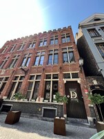 Egy téglából épült épület, nagy ablakokkal, és egy „Logies 28 Bruges” feliratú táblával.
