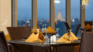 A dining table set with yellow napkins, wine glasses, and cutlery, with a view of the Eiffel Tower in the background. - Jasmine Palace Hotel (Yangon)