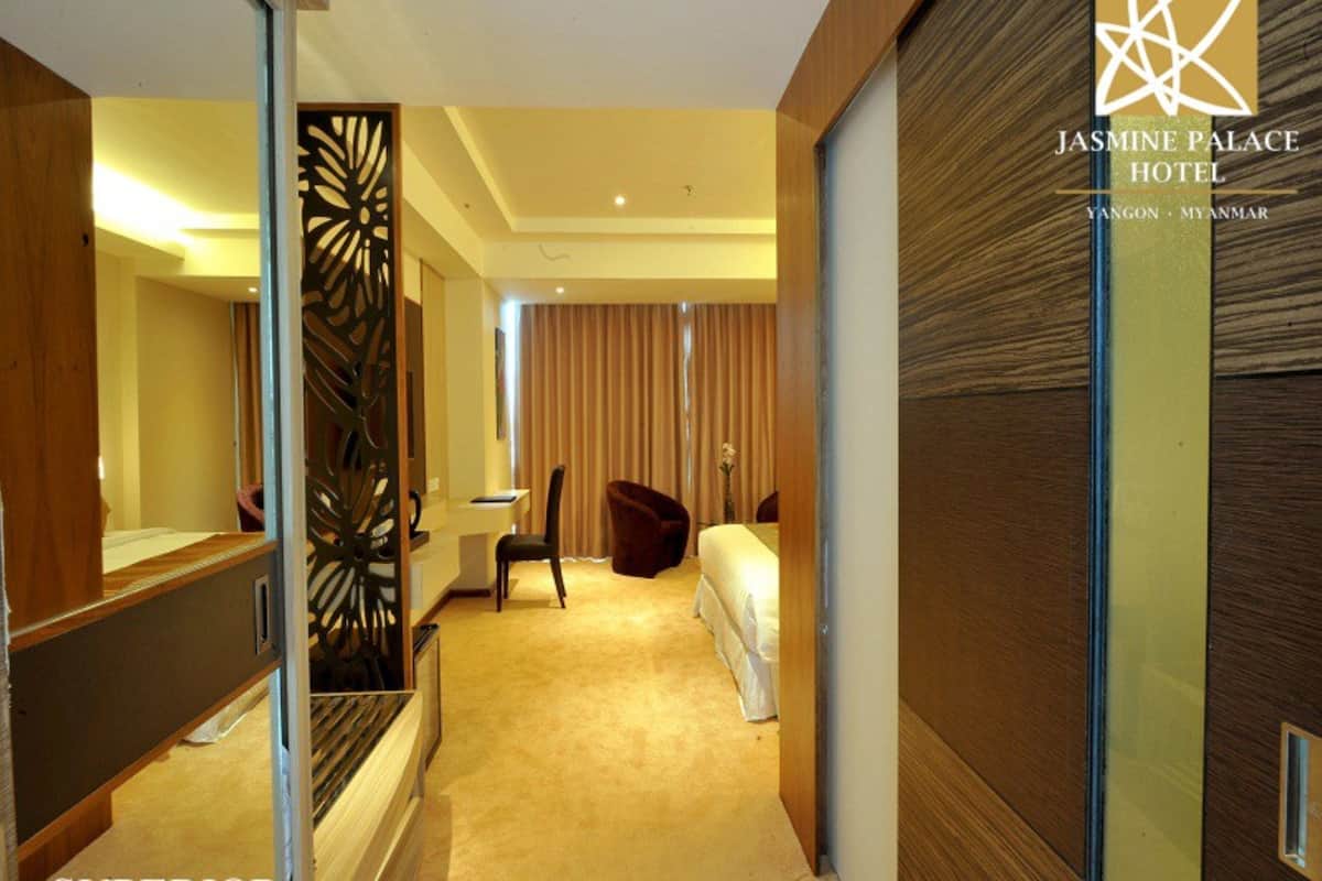 A hotel room with a bed, a desk, a chair, and a decorative partition.
