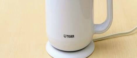 Una tetera eléctrica blanca con asa y cable de alimentación.