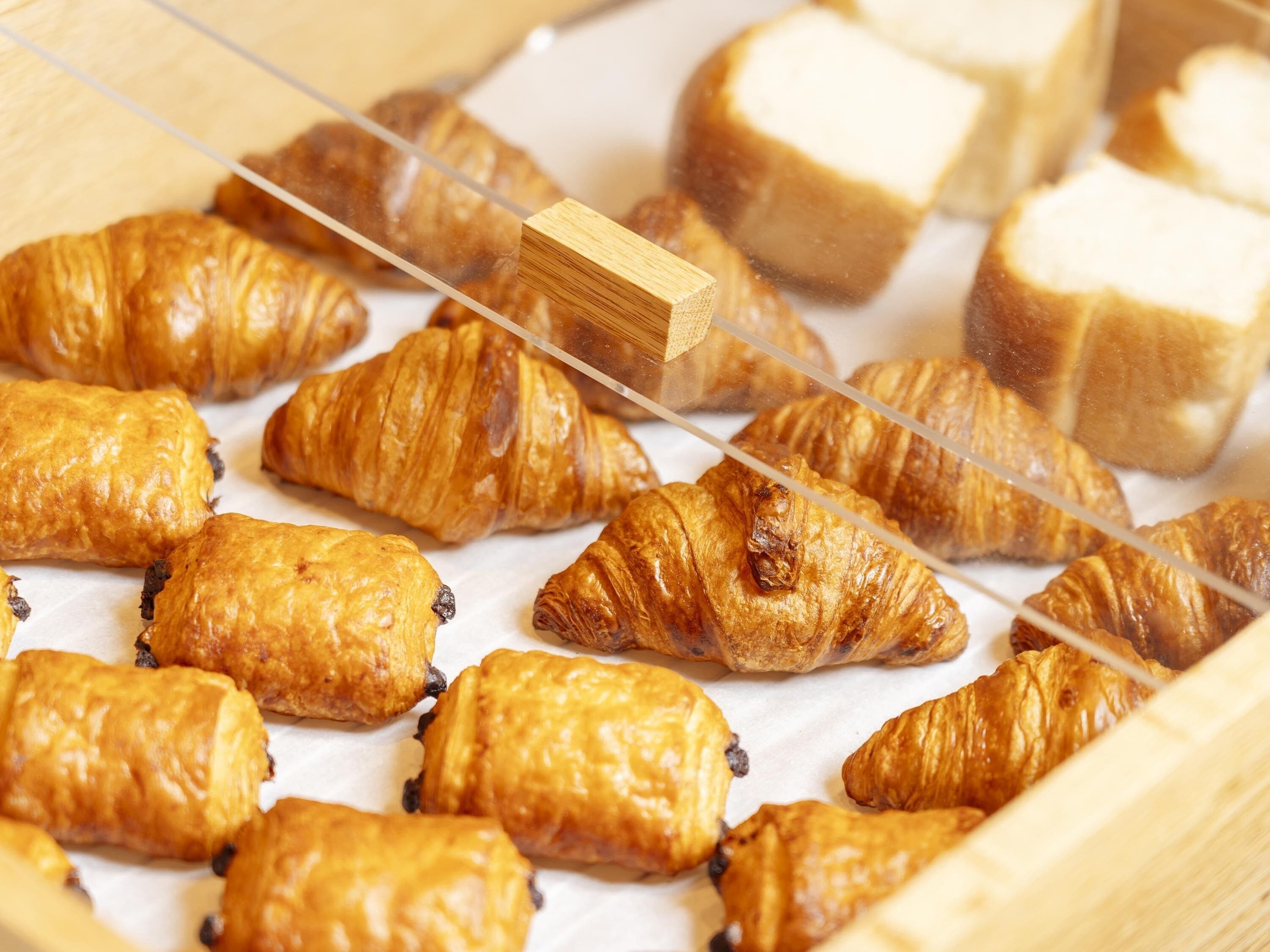 A display of assorted pastries, including croissants and bread, arranged on a wooden surface.