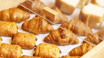 A display of assorted pastries, including croissants and bread, arranged on a wooden surface.