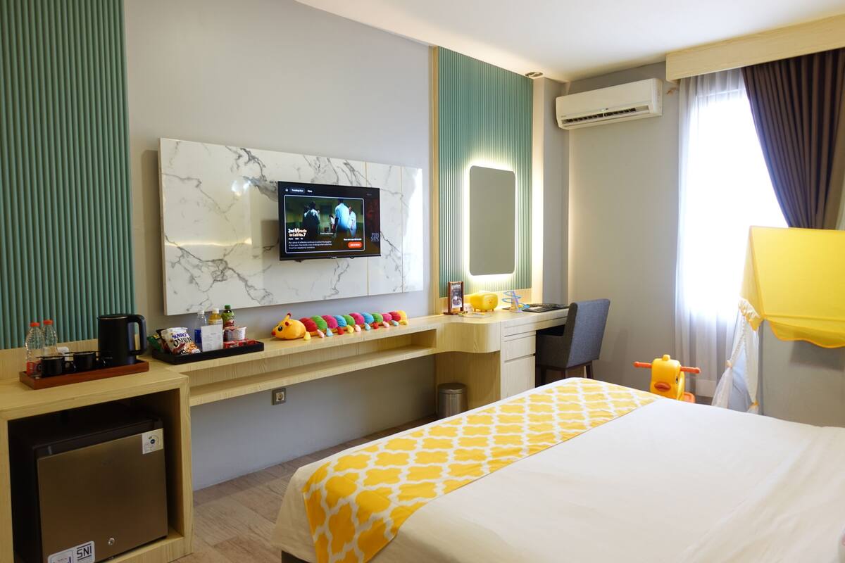 A hotel room with a bed, desk, and TV.