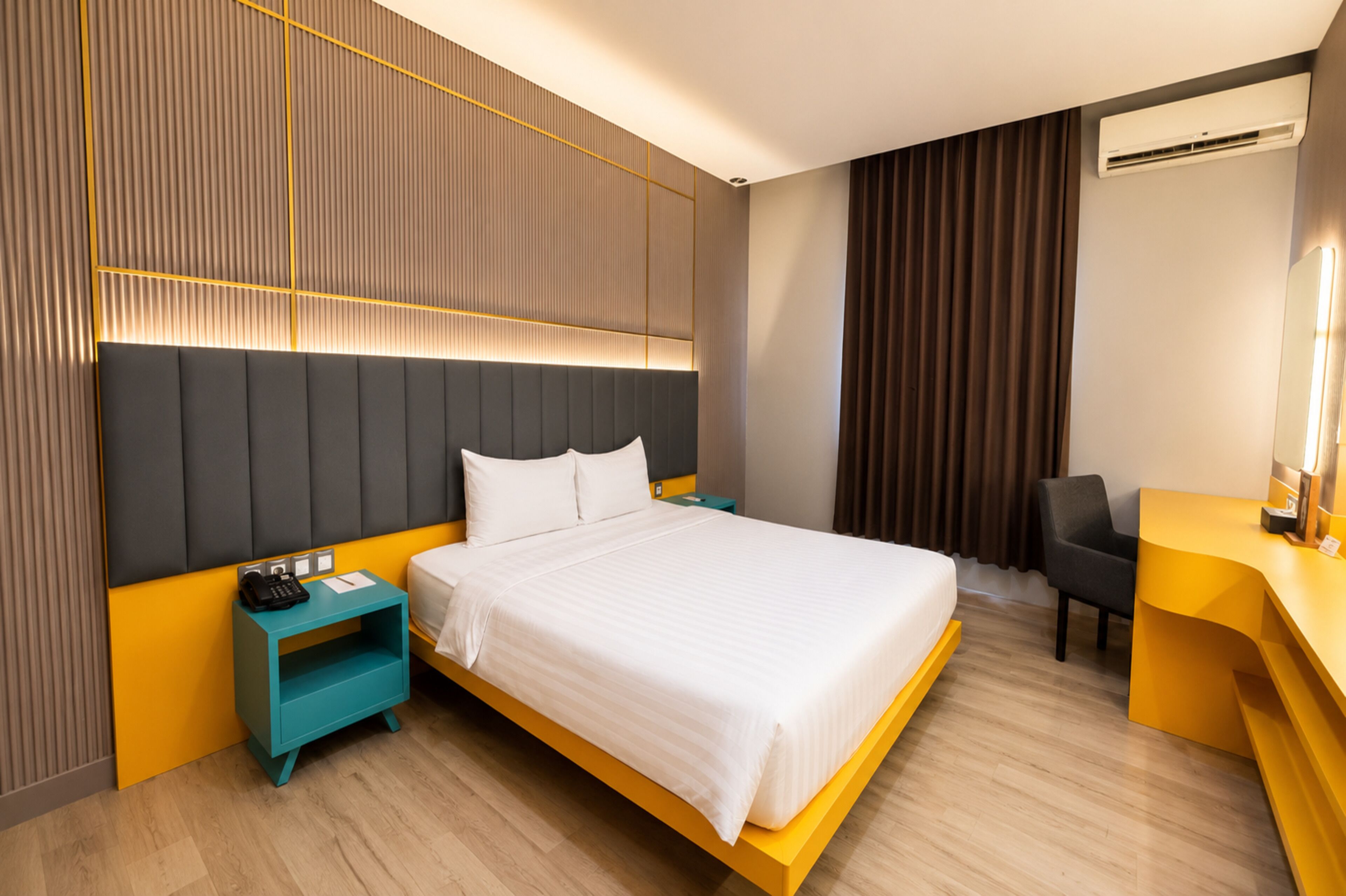 A hotel room with a large bed, a desk, a chair, and a nightstand.