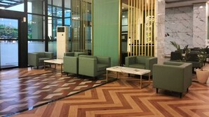 A modern lobby with green seating, a patterned floor, and a marble wall. - Grand Kangen Hotel Urip Sumoharjo Yogyakarta (Yogyakarta)