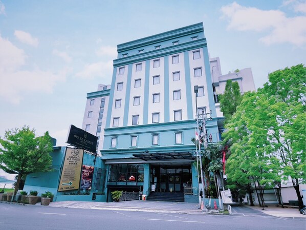 Ein Hotel mit hellblauer Fassade, mehreren Stockwerken und einem markanten Eingang.