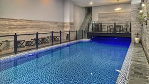 An indoor swimming pool with a tiled floor and a staircase leading to an upper level. - Grand Kangen Hotel Urip Sumoharjo Yogyakarta (Yogyakarta)
