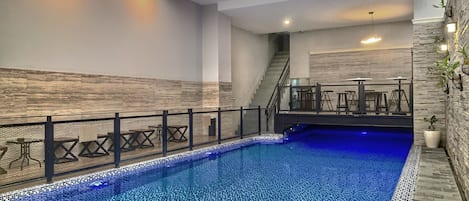 An indoor swimming pool with a tiled floor and a staircase leading to an upper level.