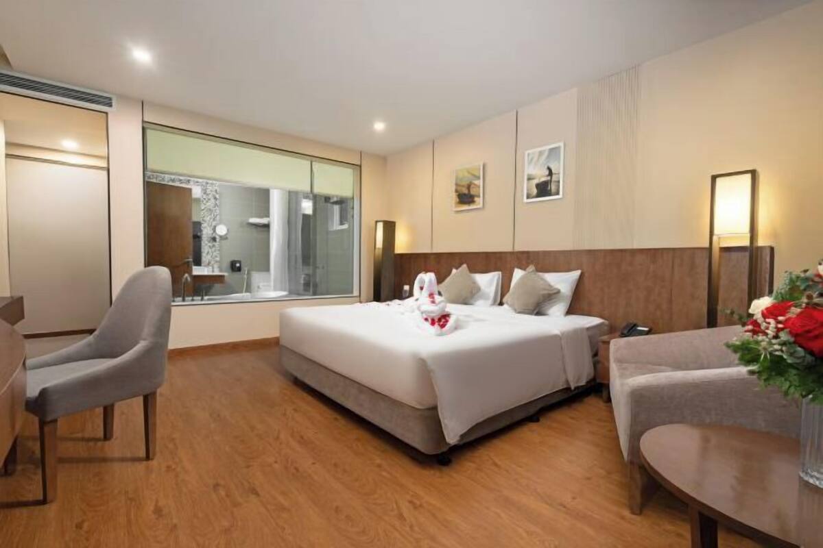 Una habitación de hotel con cama, una silla, una mesa y un espejo.