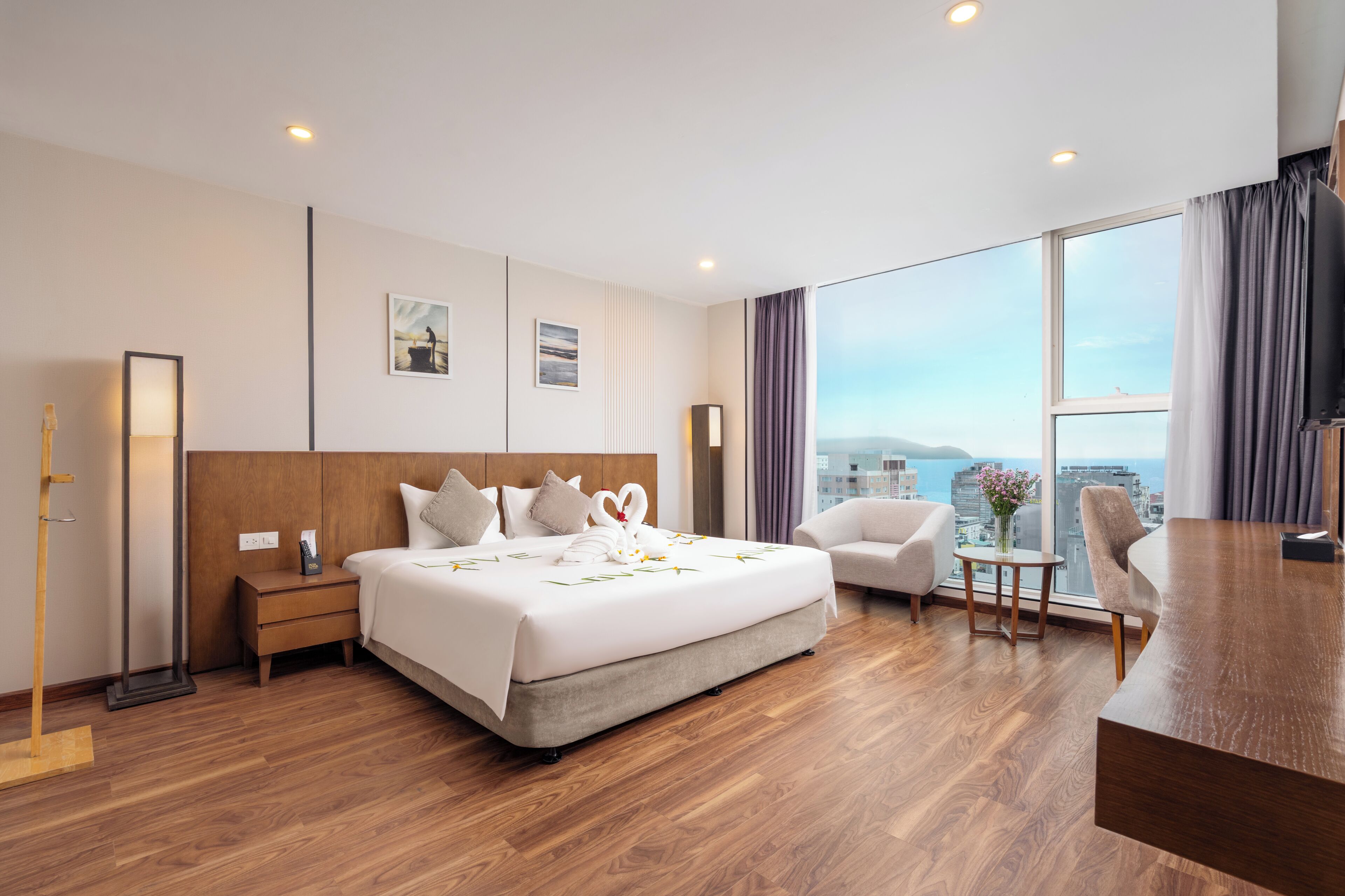 Habitación de hotel con una cama grande, un escritorio, una silla y vistas a la ciudad.