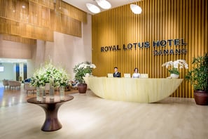 Un comptoir d'accueil moderne à l'hôtel Royal Lotus de Da Nang, avec un décor en bois et une table centrale agrémentée de plantes en pot.