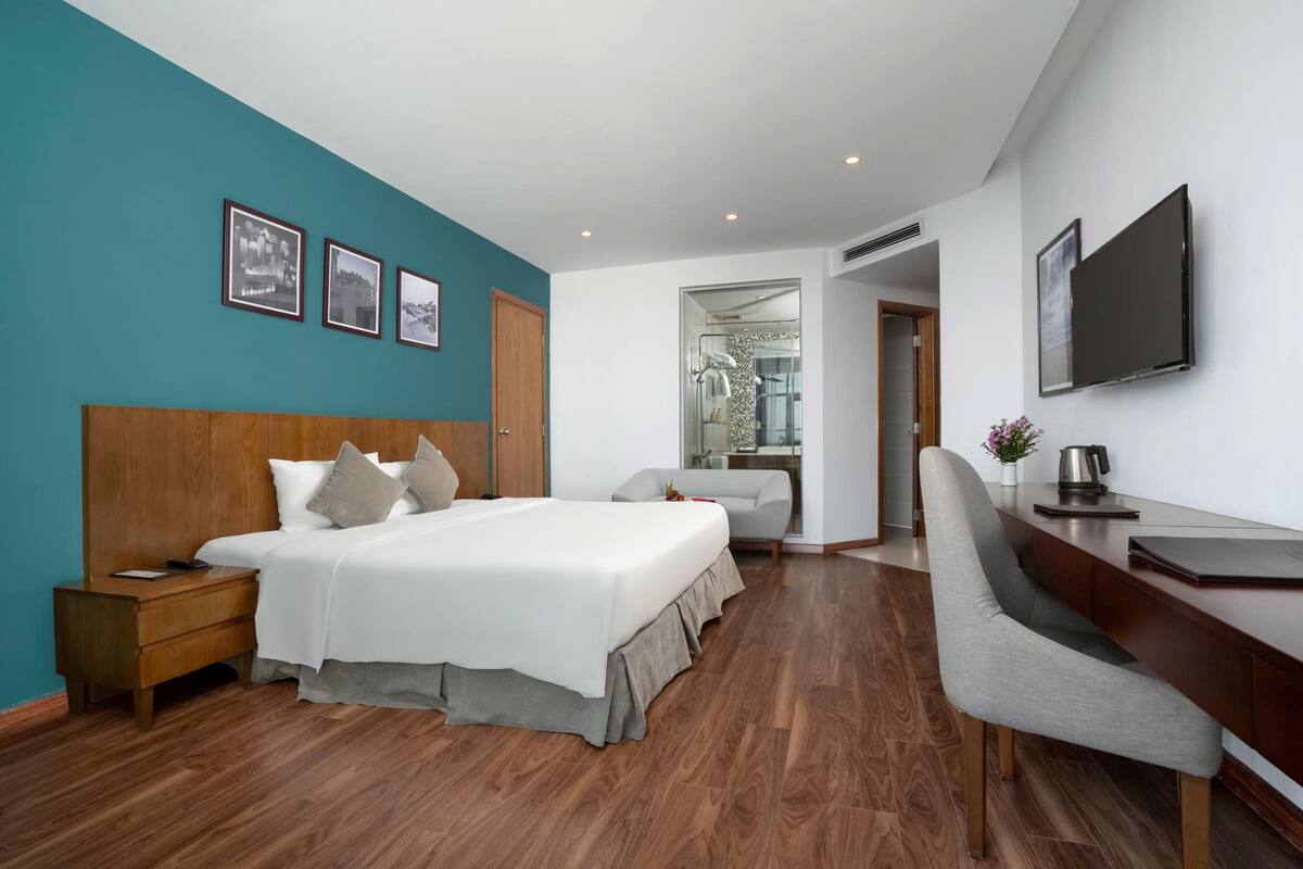 Una habitación de hotel moderna con una cama grande, un escritorio y zona de ducha.