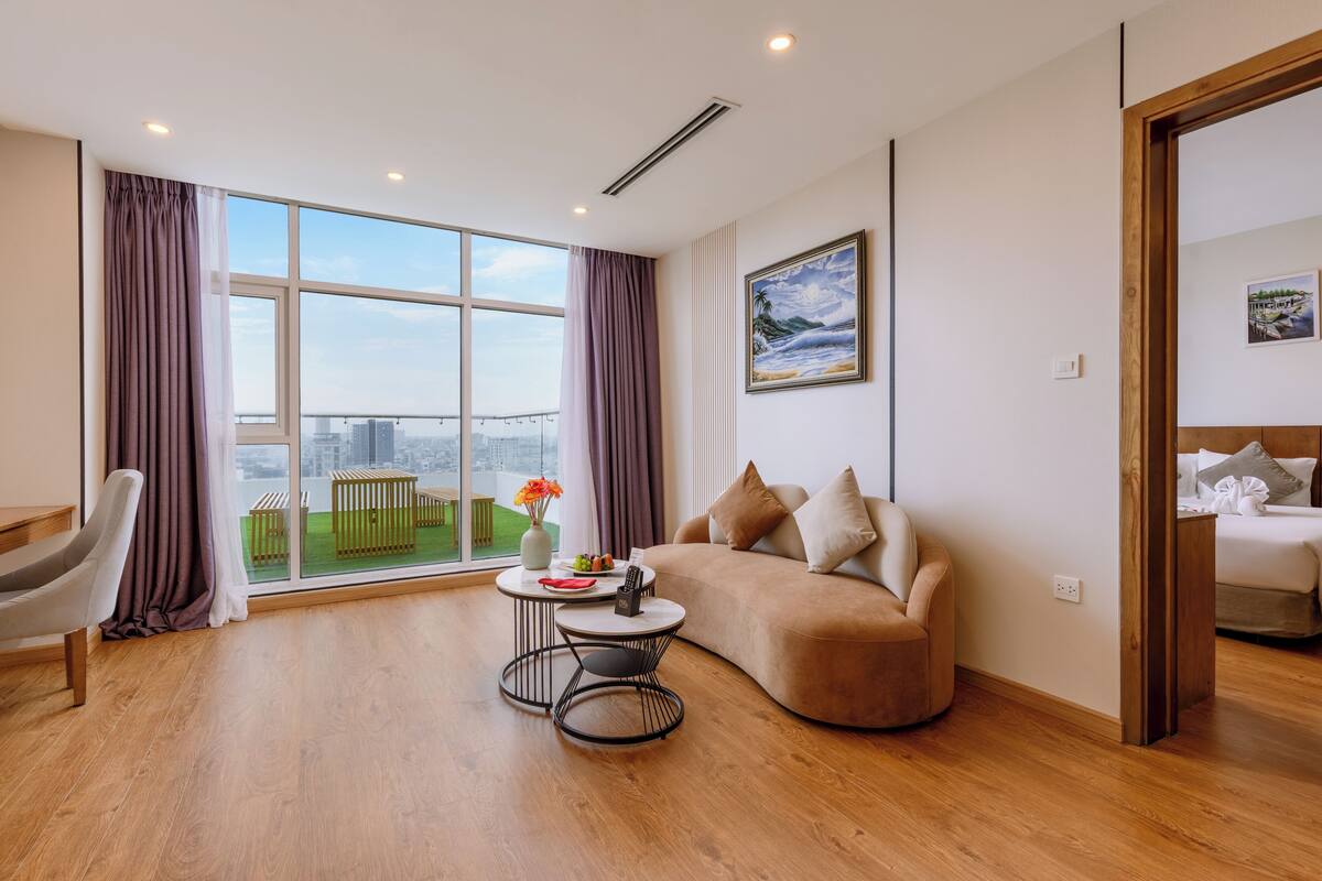 Una sala de estar moderna con un ventanal grande, un sofá, una mesita redonda y una silla.