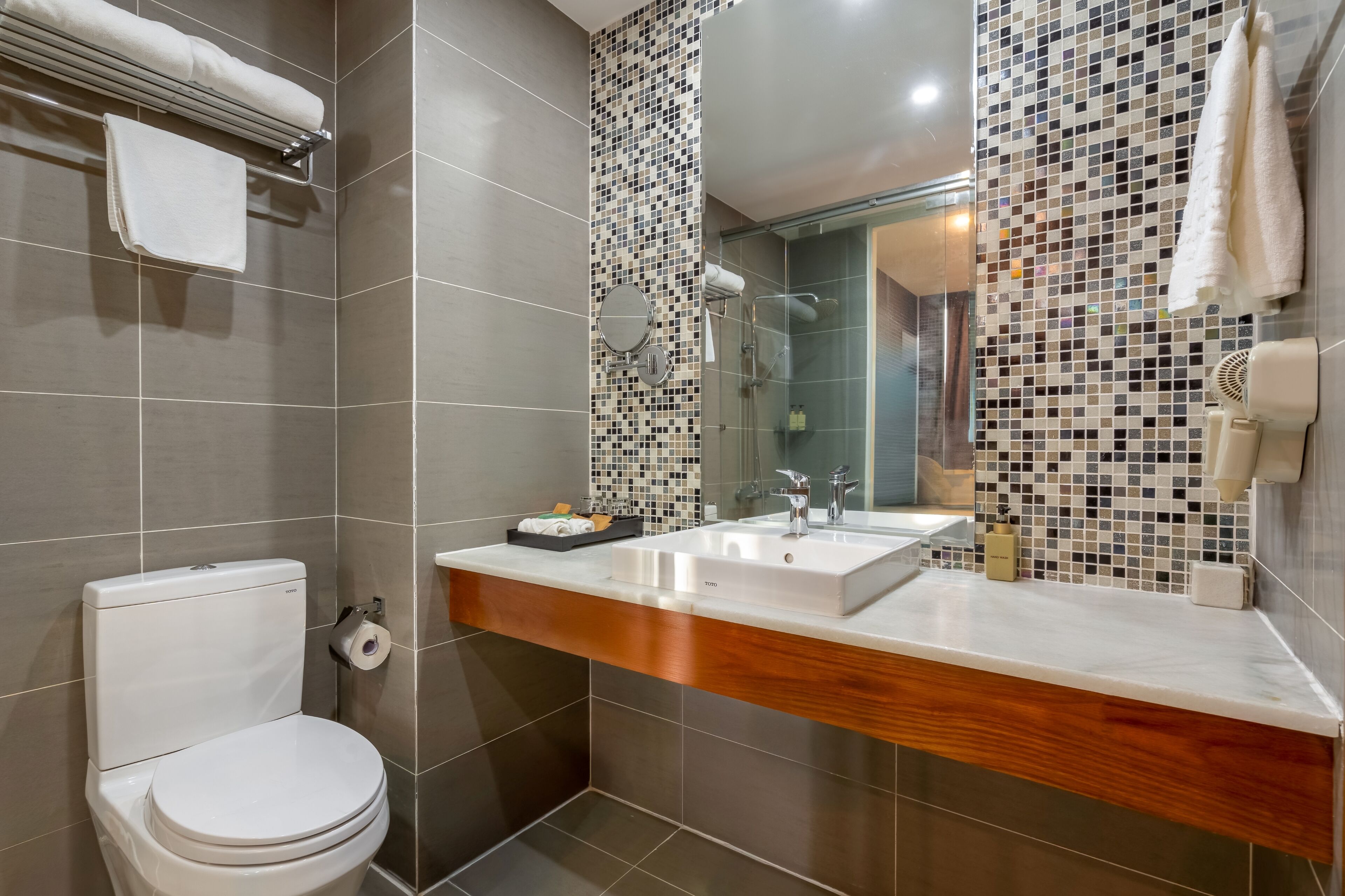 A modern bathroom with a toilet, a sink with a mirror, and a shower area.