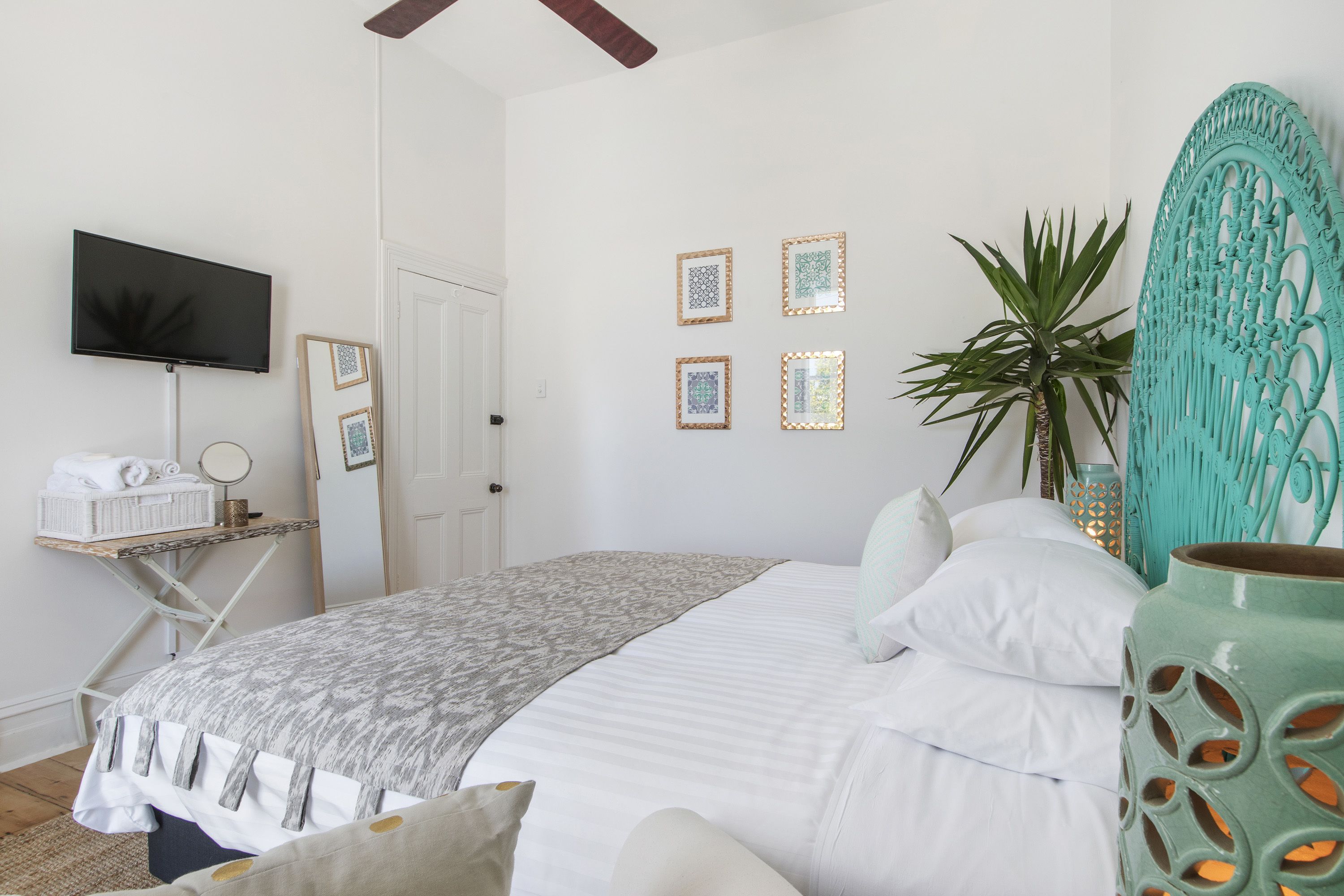 Un dormitorio ordenado con cama, mesita de noche, televisor y objetos decorativos.