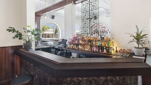 A bar area with a wooden counter, potted plants, and a variety of liquor bottles. - The Local Hotel (South Fremantle)
