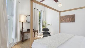 A bedroom with a bed, a desk, a chair, a lamp, and a ceiling fan.