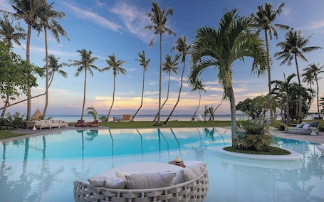 Una piscina al aire libre, sombrillas, sillones reclinables de piscina
