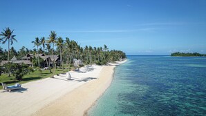 A beach resort with thatched-roof buildings, a sandy beach, and clear blue waters. - Nay Palad Hideaway (General Luna)