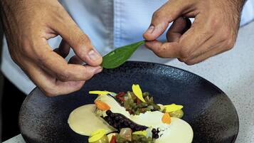 Una persona colocando una hoja verde sobre un plato con comida.