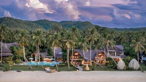 A resort with multiple buildings, a swimming pool, and palm trees. - Nay Palad Hideaway (General Luna)