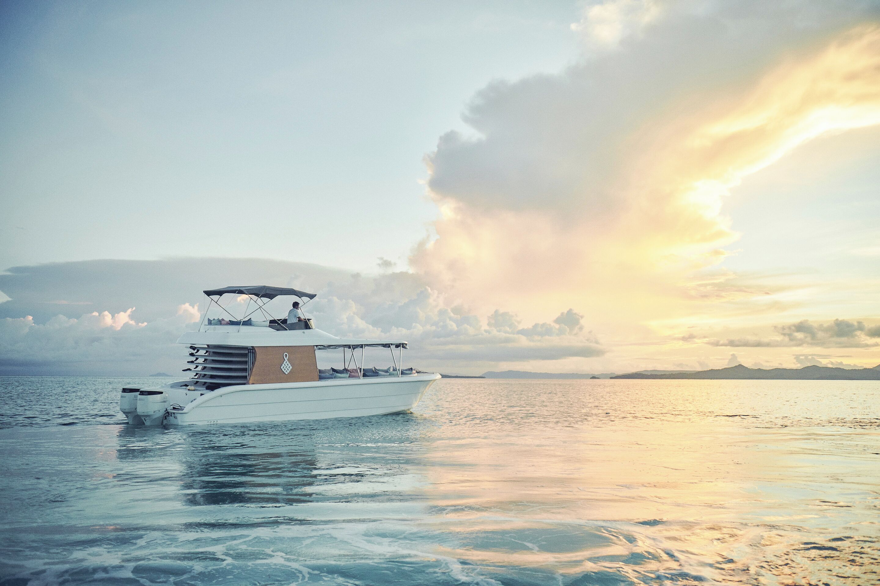 A white yacht on calm waters with a clear sky and distant land in the background.