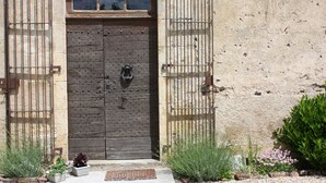 A rustic wooden door with a metal gate, set in a stone wall with a small window above. - Château Latour (Fours)