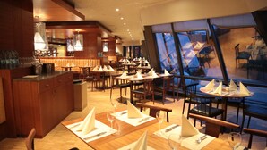 A restaurant with wooden furniture, tables set with white napkins and wine glasses, and a bar area with bottles and glasses. - Atakoy Marina Park Hotel Residences (Istanbul)