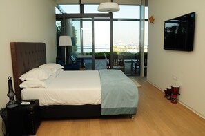 A modern hotel room with a large bed, a view of the sea, and a balcony with seating. - Atakoy Marina Park Hotel Residences (Istanbul)